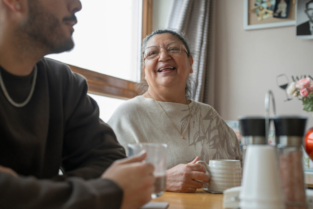 Woman sat drinking from a mug and laughing by a man