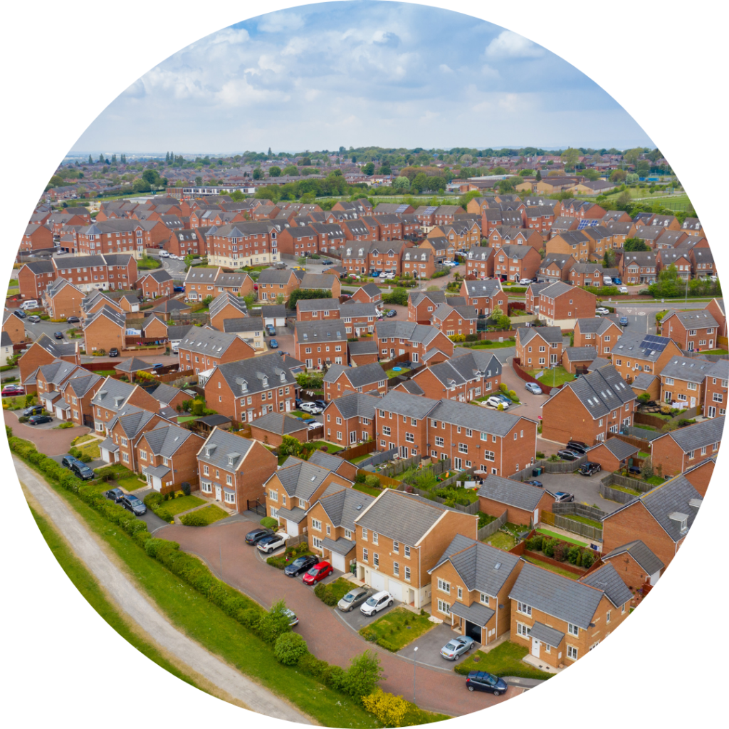 Aerial photo of a typical British housing estate in the village of Middleton in Leeds West Yorkshire in the UK, showing a top down drone view of suburban streets, roads and rows of mostly red brick houses. The sky is blue and cloudy