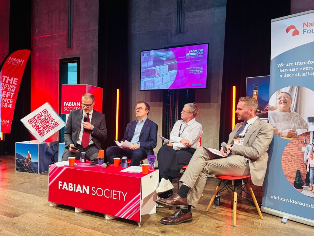 Four people sit behind a table, each with microphones - three men and a woman. The table in front of them says 'Fabian Society'